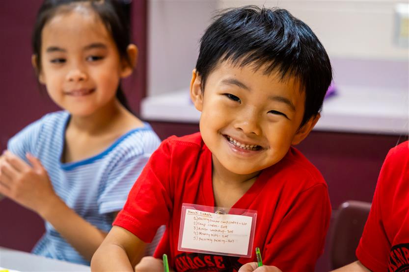 A boy wearing a red shirt smiles